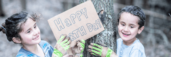 Two kids holding a handmade sign that says happy earth day